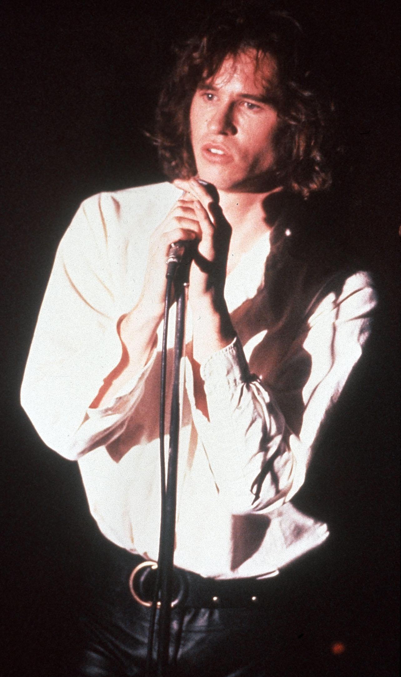 Val Kilmer as Jim Morrison singing into a microphone.
