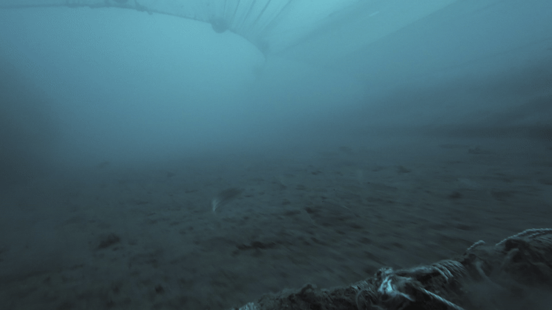 Underwater image of a fishing net against the ocean floor.