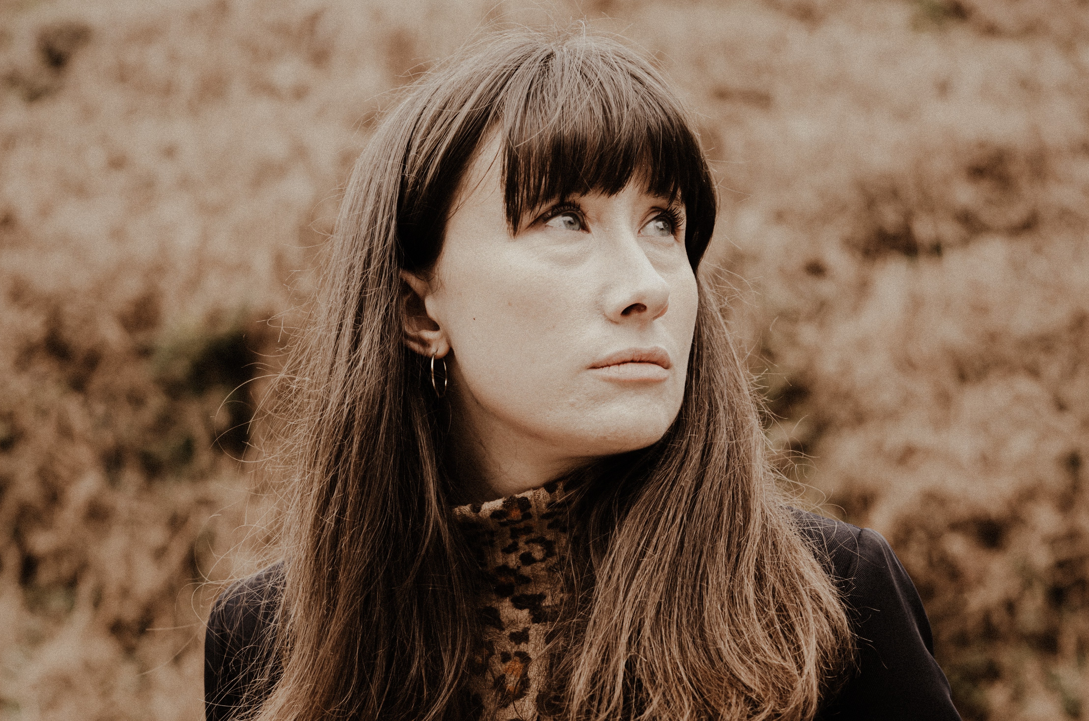 Portrait of a woman looking up, wearing a leopard print top and black jacket.