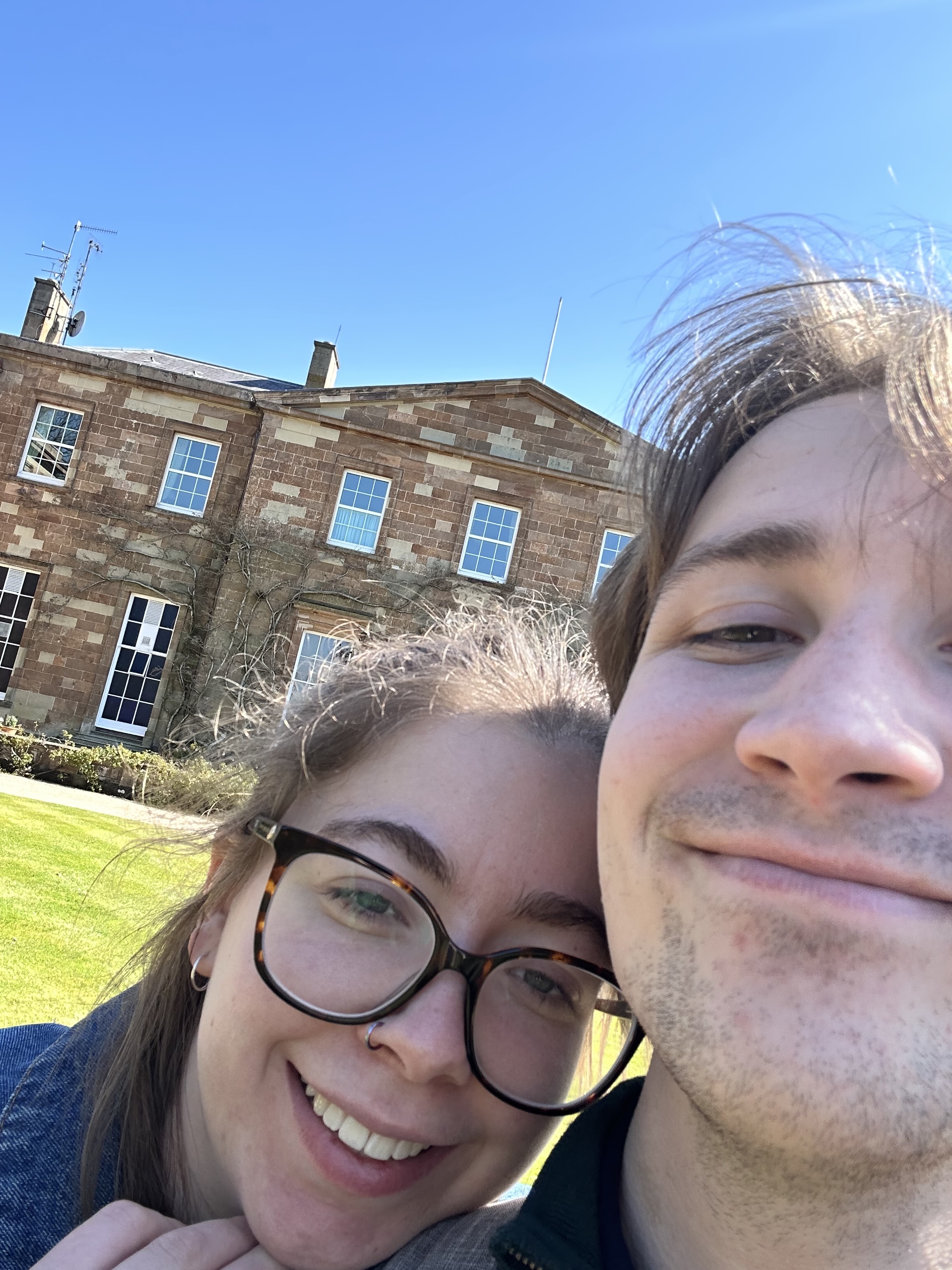 Selfie of a couple in front of a stone building.