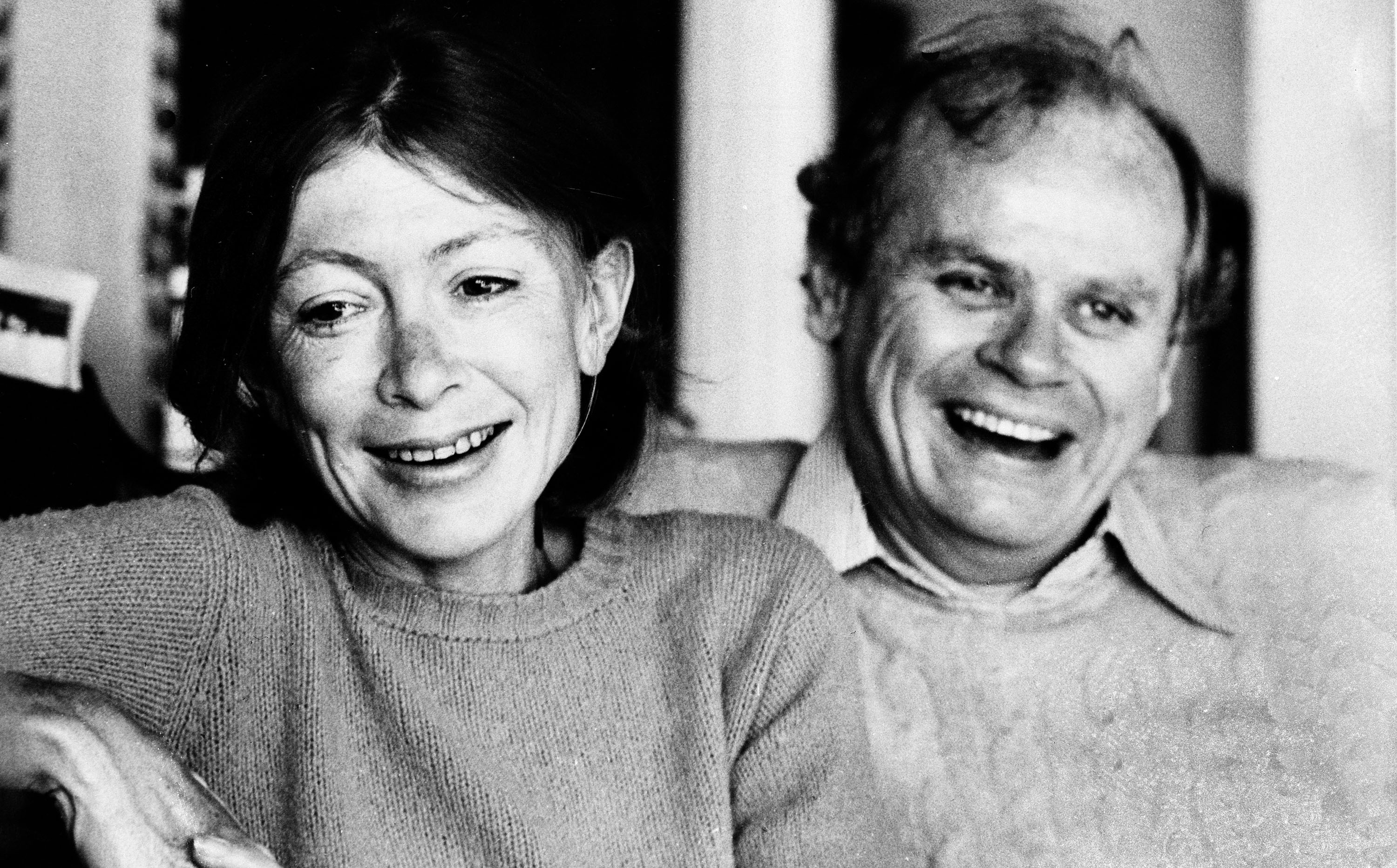Black and white photo of Joan Didion and John Dunne smiling during an interview.